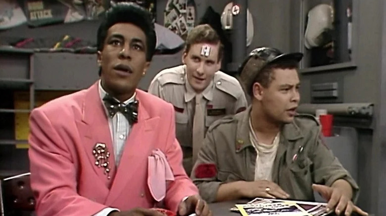 Cat (Danny John-Jules), Rimmer (Chris Barrie), and Dave Lister (Craig Charles) sit puzzled at a table in Red Dwarf