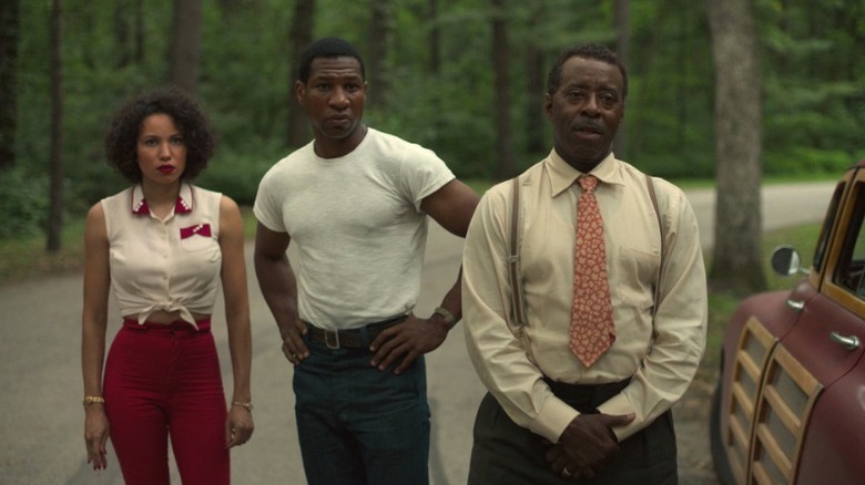 Leti (Jurnee Smollett), Atticus (Jonathan Majors), and George (Courtney B. Vance) standing next to their car on Lovecraft Country S1E1