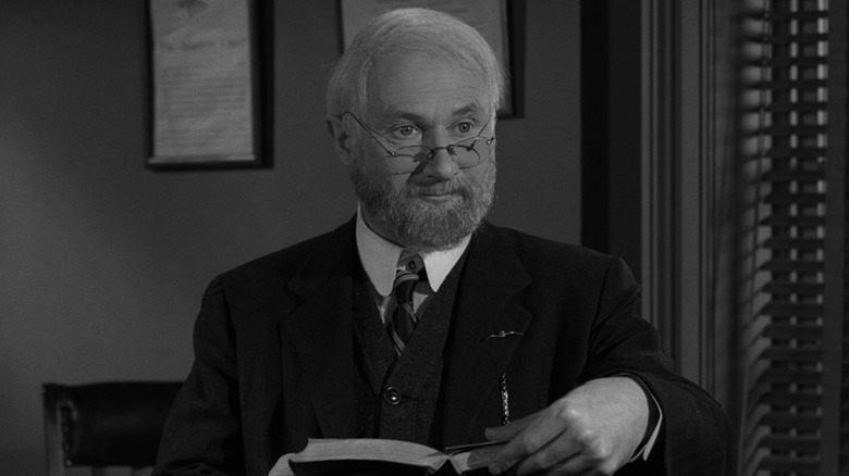 Professor Ellis Fowler (Donald Pleasance) holding a book on "The Twilight Zone."