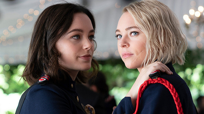 Scylla in blue uniform with hand on shoulder of Raelle