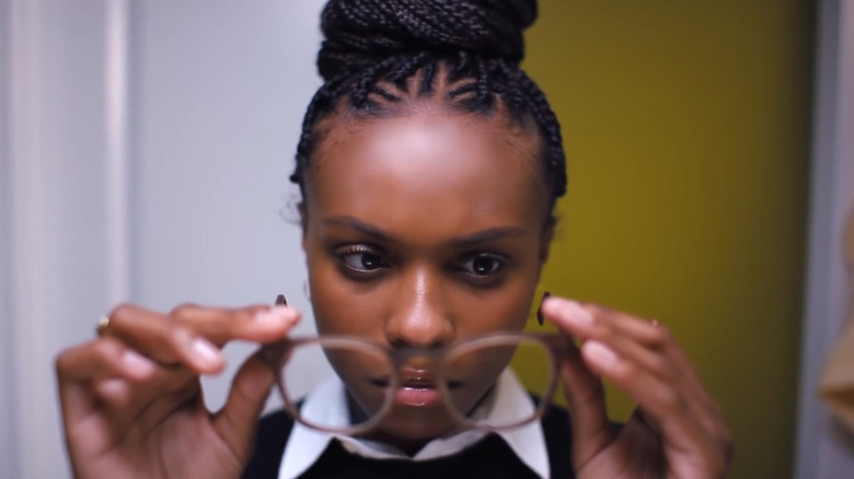 Kaci Walffall as Naomi McDuffie looking at her glasses in Naomi