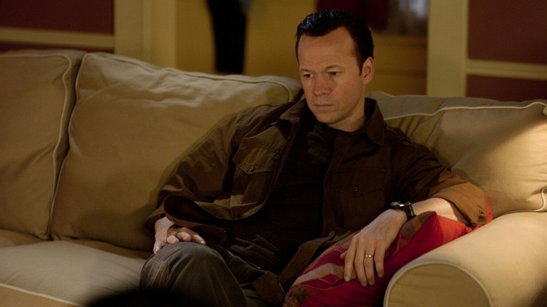 Donnie Wahlberg as Jim Holland sitting on a couch in Runaway