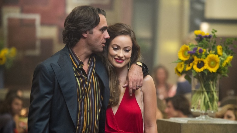 Richie Finestra (Bobby Cannavale) whispers to Devon Finestra (Olivia Wilde) while walking with her in a restaurant in Vinyl