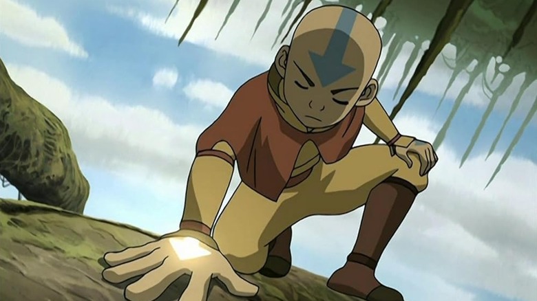 Aang crouching and pressing his hand against a tree.