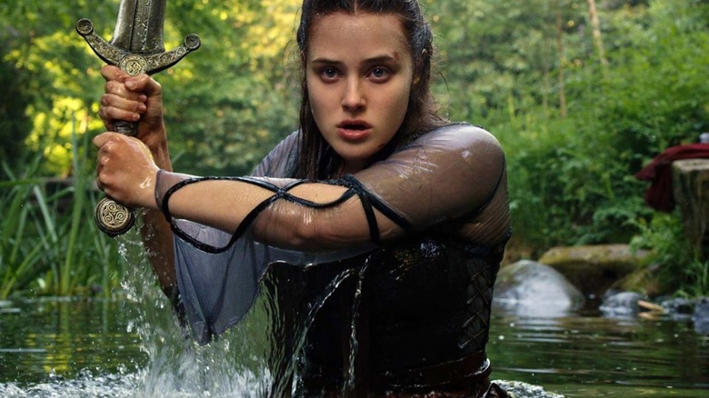 Nimue (Katherine Langford) emerges from a lake wielding a sword in Cursed (2020)