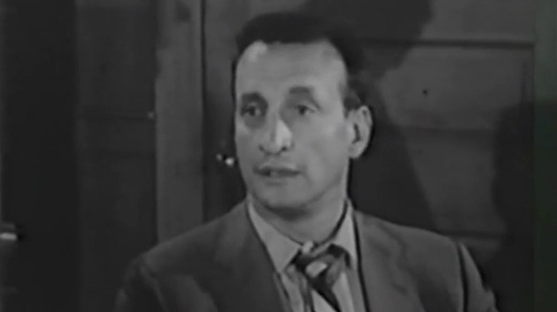 Neil Brock sitting on talking on East Side/West Side S1E5