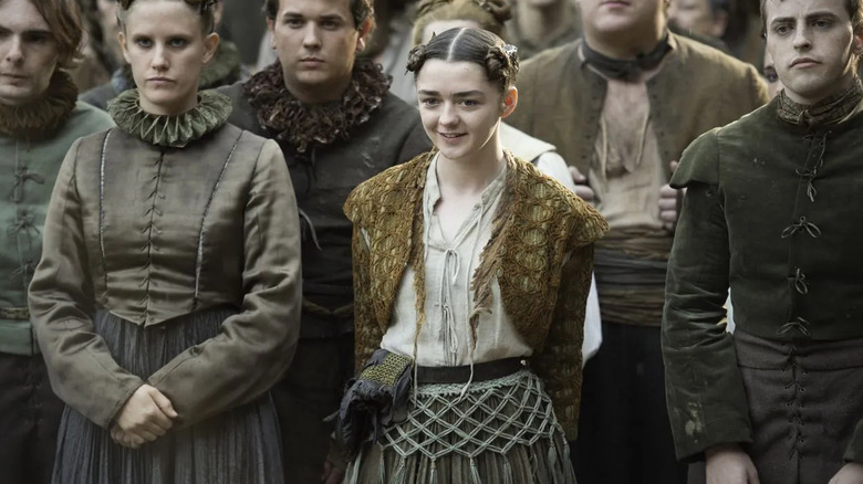 Maisie Williams as Arya Stark smiles in a crowd on Game of Thrones