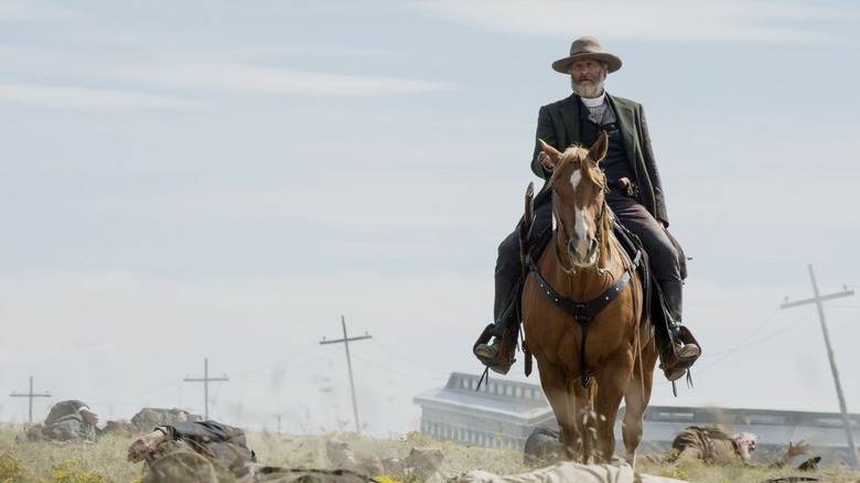 Frank Griffin (Jeff Daniels) rides a horse over a field of bodies in Godless