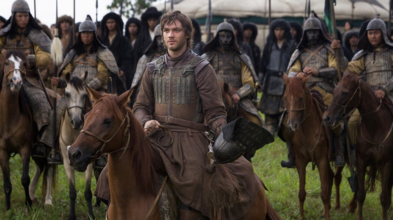Marco Polo (Lorenzo Richelmy) takes off his helmet while surrounded by Mongolian soldiers on horseback in Marco Polo