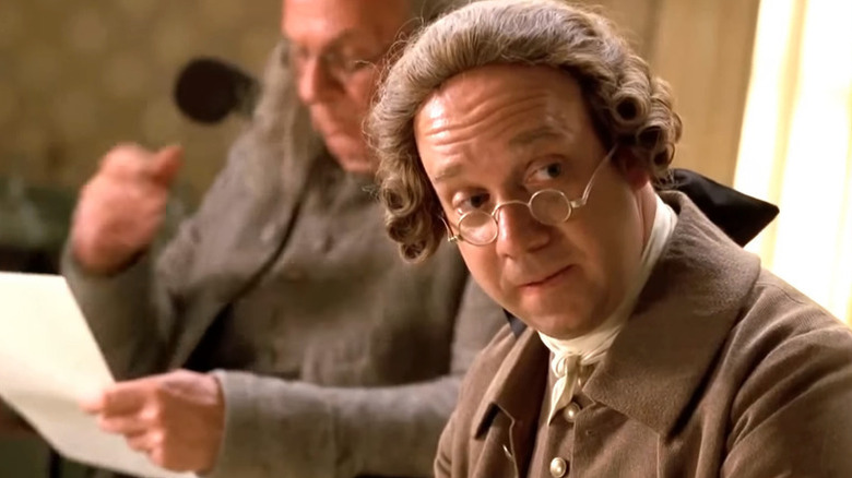 John Adams (Paul Giamatti) sits next to Ben Franklin (Tom Wilkerson) in John Adams