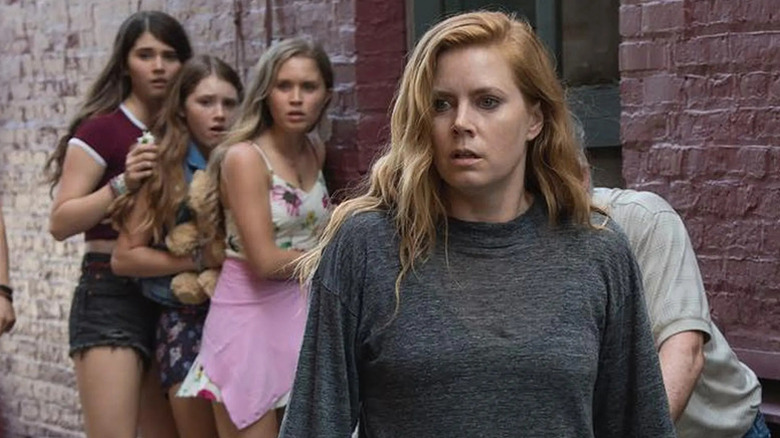 Camille Preaker (Amy Adams) stands in an alley with shocked girls in Sharp Objects