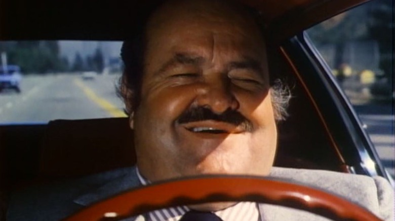 Frank Cannon (William Conrad) smiles jovially while driving in Cannon