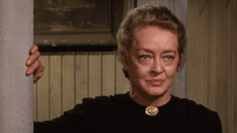 Etta Stone (Bette Davis) peers around a corner in Gunsmoke