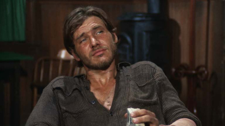 Hobey (Harrison Ford) warily holds a deck of cards in Gunsmoke