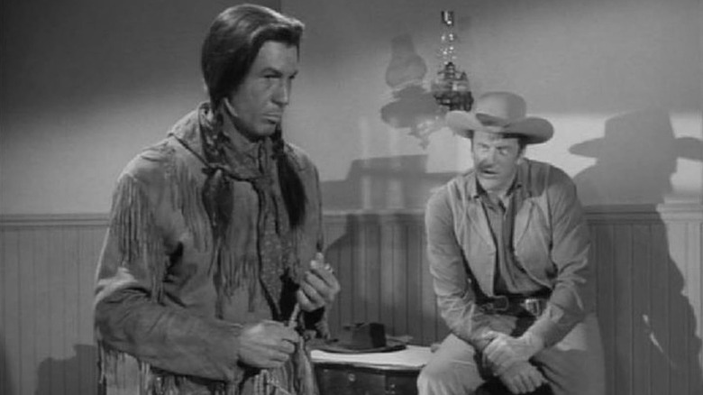 John Walking Fox (Leonard Nimoy) stands contemplatively as Matt Dillon (James Arness) speaks to him in Gunsmoke