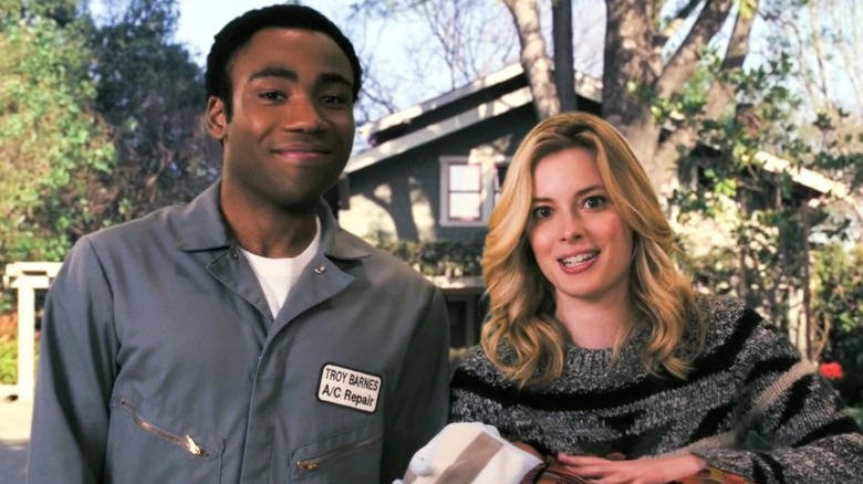 Donald Glover and Gillian Jacobs as Troy and Britta standing together and smiling in Community