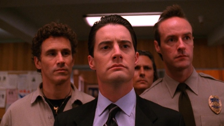 Kyle MacLachlan as Special Agent Dale Cooper, standing with Deputy Brennan and Deputy Hawk in Twin Peaks.