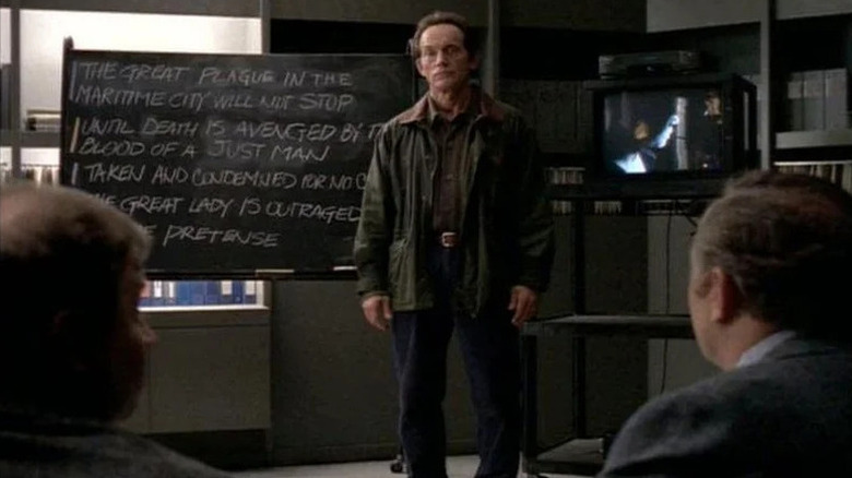 Frank Black (Lance Henriksen) standing next to a chalk board on "Millennium."