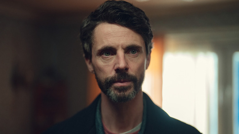 Carl Morck (Matthew Goode) standing in a dimly lit room on "Dept. Q."