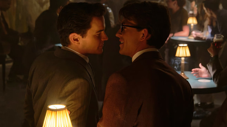 Matt Bomer as Hawk standing very close to Jonathan Bailey as Tim in a bar in Fellow Travelers