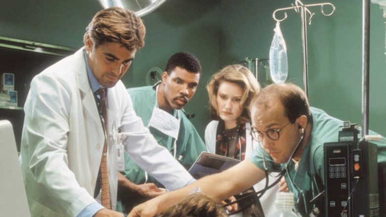 Dr. Doug Ross (George Clooney), Dr. Peter Benton (Eriq La Salle), Dr. Susan Lewis (Sherry Stringfield) and Dr. Mark Greene (Anthony Edwards) examine a patient on ER