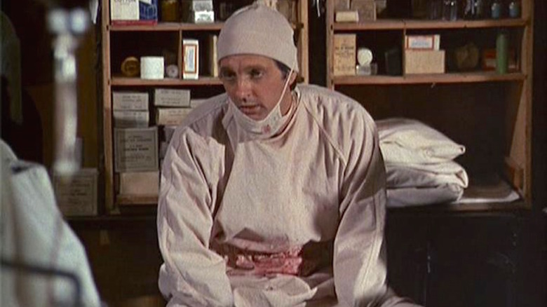 An exhausted Hawkeye Pierce (Alan Alda) sits in a supply room in M*A*S*H