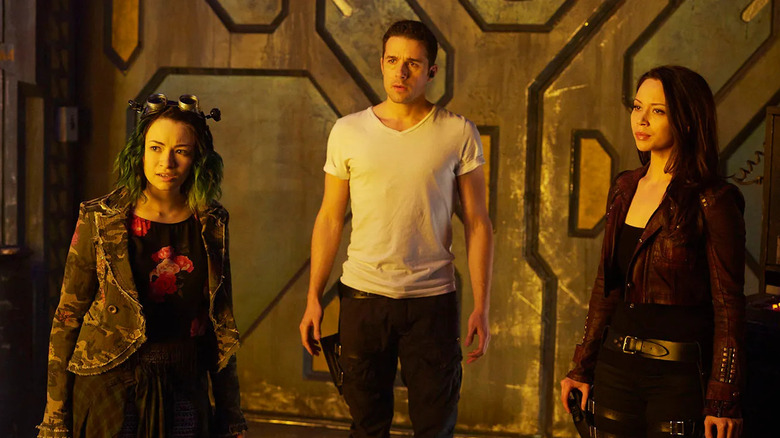 Emily Kolburn (Jodelle Ferland), Derrick Moss (Marc Bendavid), and Rebecca (Melissa O'Neil) stand by a large set of metal doors in Dark Matter (2015)
