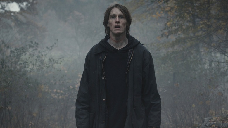 A dirty Jonas Kahnwald (Louis Hofman) stands in a foggy forest in Dark