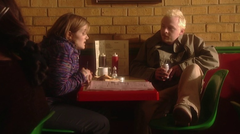 Daisy and Tim sitting together at a café table on Spaced.