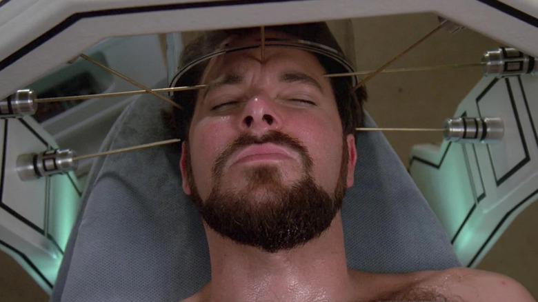 Will Riker (Jonathan Frakes) lies unconscious with his head in a pointed device in Star Trek: The Next Generation