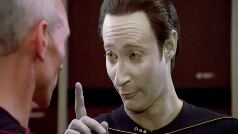 Data (Brent Spiner) raises a finger with a goofy look on his face while speaking to Jean-Luc Picard (Patrick Stewart) in Star Trek: The Next Generation