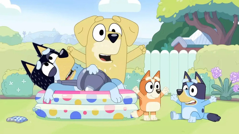 Animated black and blue dog (Bandit) laying in kiddie pool, yellow dog (Lucky's dad) standing behind him, orange puppy (Lucky) next to pool alongside black and blue puppy (Bluey) on Bluey