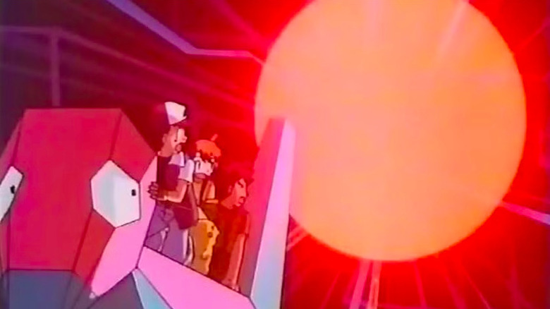 Ash, Misty, and Brock standing on large red creature looking at orange ball of light in Pokémon