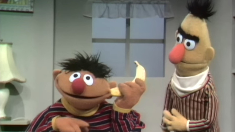 Ernie with a banana in his ear standing next to Bert in Sesame Street