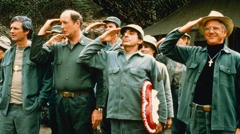 Cpl. Maxwell Klinger, Hawkeye, Father Mulcahy, and Winchester standing at attention in M*A*S*H