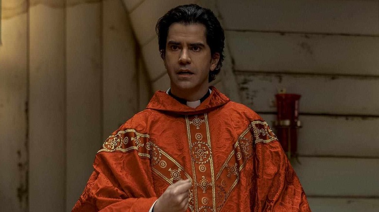 Hamish Linklater as Father Paul in an orange robe in Midnight Mass