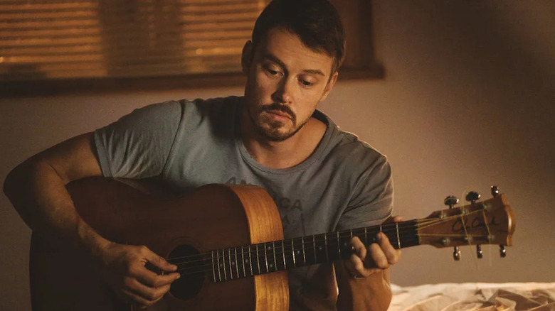 John Tavner plays the guitar in his apartment in Patriot.