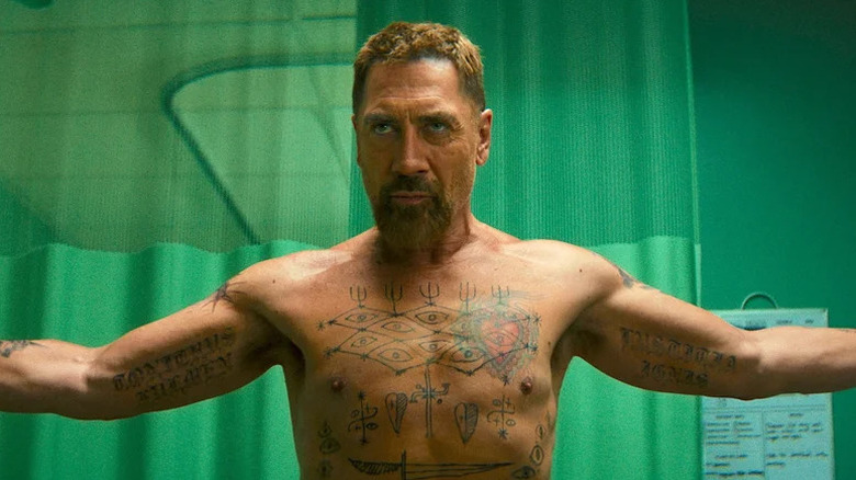 Shirtless Javier Bardem as Max Cady in front of green curtains with many tattoos visible in Cape Fear