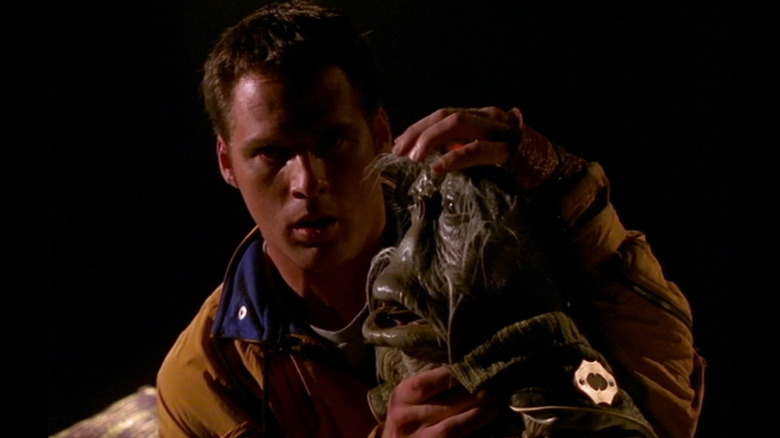 John Crichton (Ben Browder) holding Dominar Rygel XVI's (voiced by Jonathan Hardy) head and looking scared in Farscape