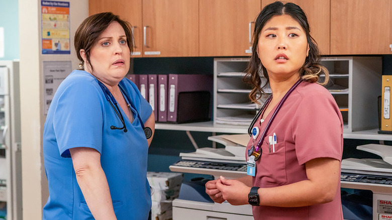 Allison Tolman as Alex in blue scrubs next to Kahyun Kim as Serena in pink scrubs in St. Denis Medical