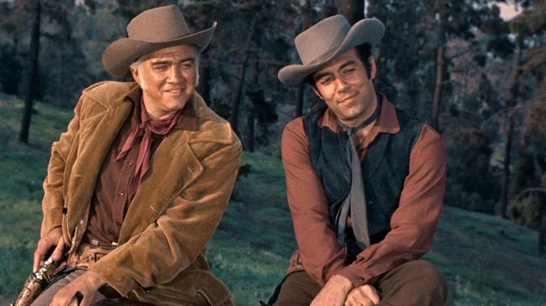 Ben Cartwright (Lorne Greene) sits on a horse next to Adam Cartwright (Pernell Roberts) in Bonanza