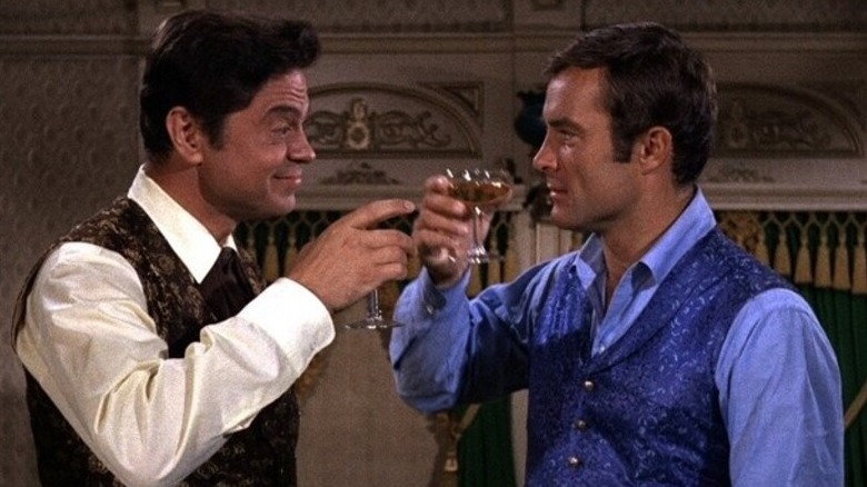 Artemus Gordon (Ross Martin) and Jim West (Robert Conrad) toast each other in The Wild Wild West