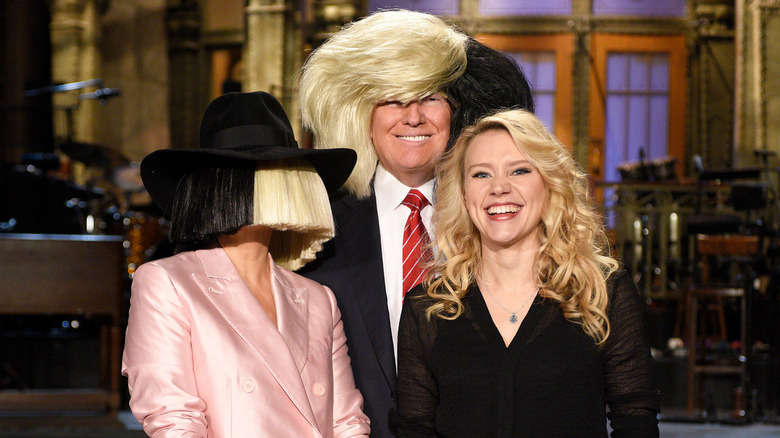 Donald Trump wearing a Sia wig while standing with Sia and Kate McKinnon in an SNL promo