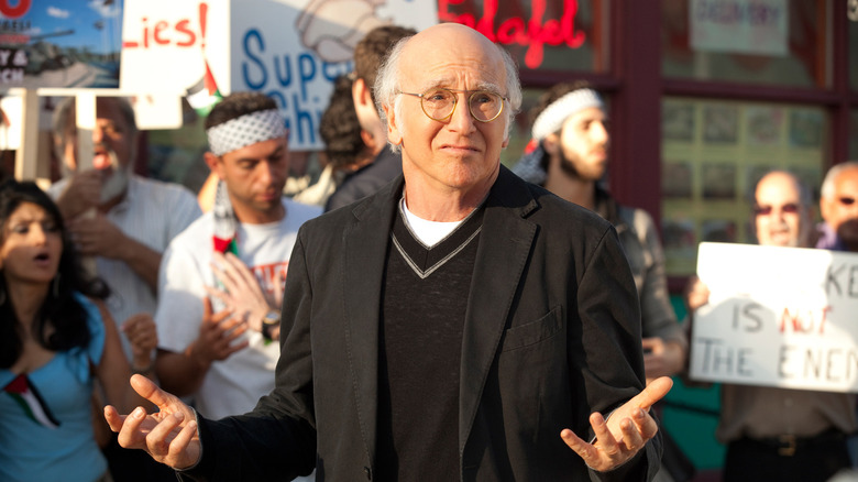 Larry David shrugging in front of protestors on Curb Your Enthusiasm