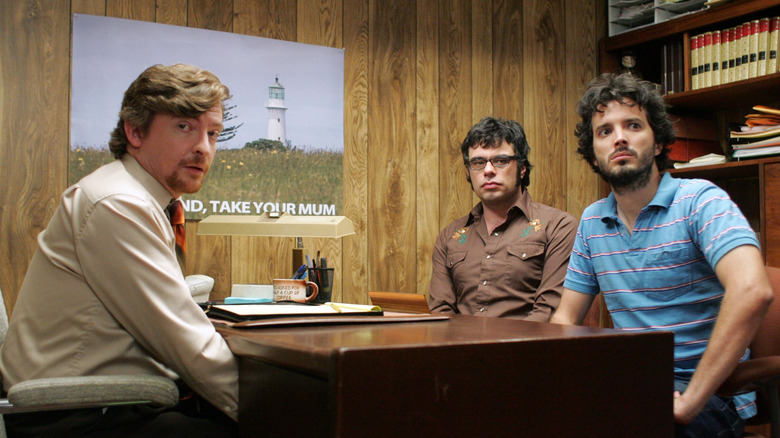 Rhys Darby as Murray sitting across from Jemaine and Bret on Flight of the Conchords