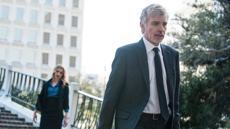 A harried Billy McBride (Billy Bob Thornton) walks down outside stairs as a woman watches in Goliath