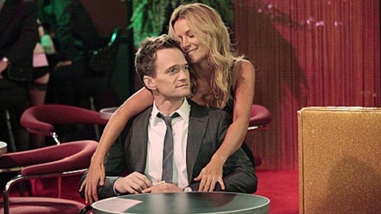 Quinn Garvey (Becki Newton) embraces Barney Stinson (Neil Patrick Harris) from behind in How I Met Your Mother