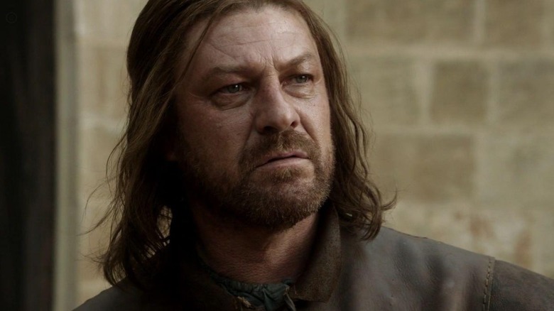 Ned Stark (Sean Bean) looking forward stood in front of a brick wall on Game of Thrones