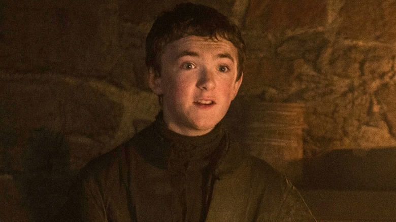 Olly (Brenock O'Connor) stood against a stone wall on Game of Thrones looking surprised
