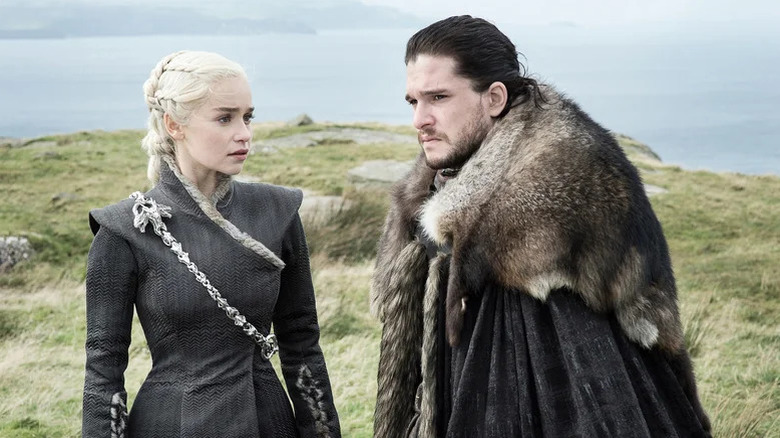 Daenerys Targaryen (Emilia Clarke) stares at a frowning Jon Snow (Kit Harington) on a grassy hill on Game of Thrones